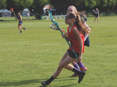 Seventh-grader Louisa Linkas sprints down the field with the ball in attempt to score a goal. This was an away game against TASIS on May 5 where the girls lost 14-13 (photo by  Tiala Bassatne).