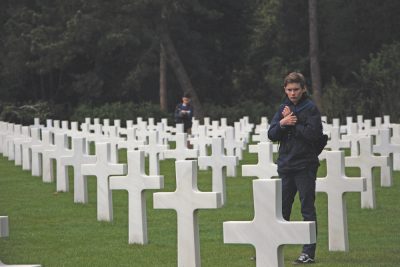 Eighth-grader Owen Sobocinski looks at the grave of an American soldier at the US Military Cemetery in Normandy. The US Cemetery is entirely symmetrical and is made up of straight lines that makes the graves appear to stretch on forever (photo by Athena Lambropoulos). 